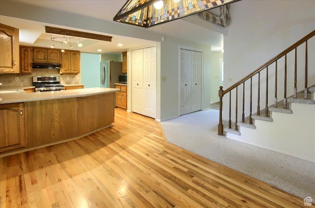 5725 S 1075 E, South Ogden, UT 84405 - kitchen with appliances with stainless steel finishes, under cabinet range hood, light wood finished floors, light countertops, and brown cabinetry