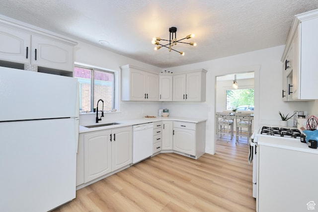 557 E Cleveland Ave, Salt Lake City, UT 84105 - kitchen with white appliances, a sink, a chandelier, light wood finished floors, and white cabinets