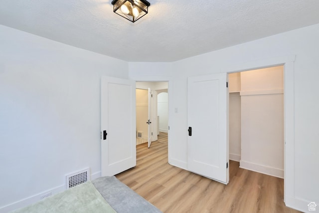 557 E Cleveland Ave, Salt Lake City, UT 84105 - unfurnished bedroom featuring light wood-type flooring, baseboards, a closet, a textured ceiling, and a spacious closet