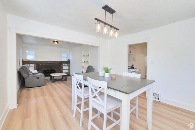 557 E Cleveland Ave, Salt Lake City, UT 84105 - dining space featuring light wood finished floors, a brick fireplace, and baseboards