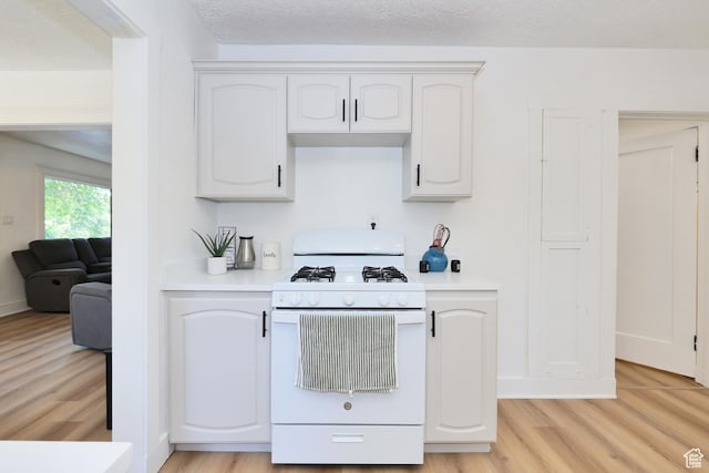557 E Cleveland Ave, Salt Lake City, UT 84105 - kitchen featuring white gas range oven, light wood-style floors, light countertops, and white cabinets