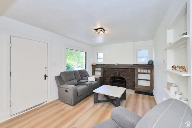 557 E Cleveland Ave, Salt Lake City, UT 84105 - living room featuring light wood-style floors, a brick fireplace, a textured ceiling, and baseboards