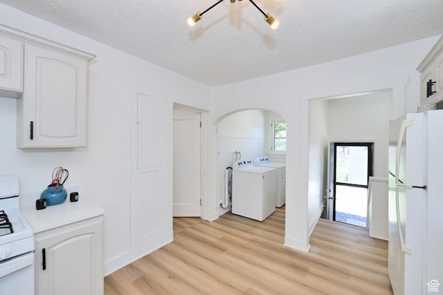 557 E Cleveland Ave, Salt Lake City, UT 84105 - washroom with washing machine and clothes dryer, light wood-style flooring, a textured ceiling, arched walkways, and baseboards