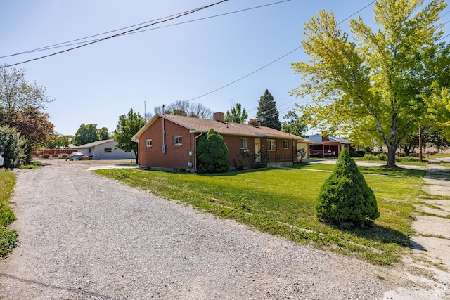 253 S 100 W, American Fork, UT 84003 - view of home's exterior with a yard, brick siding, gravel driveway, and a chimney