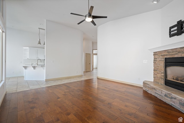 42 N 1100 W, St George, UT 84770 - unfurnished living room with light wood-style flooring, ceiling fan, a fireplace, and baseboards