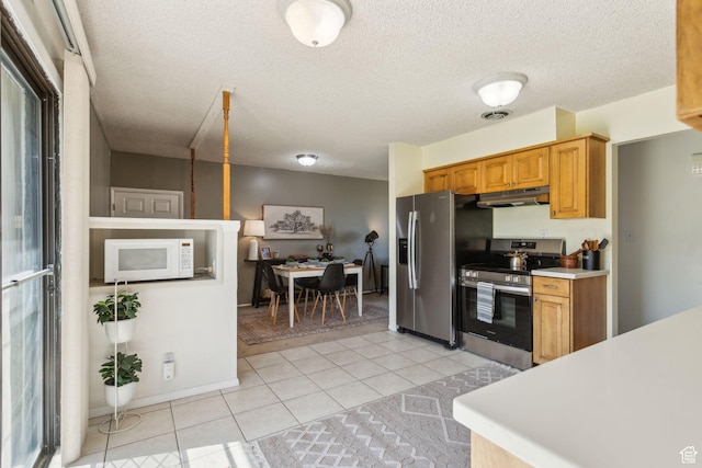 295 S 2nd St, Tooele, UT 84074 - kitchen with appliances with stainless steel finishes, under cabinet range hood, light countertops, light tile patterned floors, and a textured ceiling