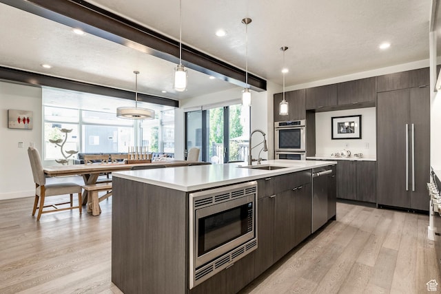 260 W 500 N Unit 4, Salt Lake City, UT 84103 - kitchen featuring a sink, stainless steel appliances, an island with sink, light wood-type flooring, and light countertops