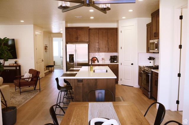 1376 Rustico, Washington, UT 84780 - kitchen featuring appliances with stainless steel finishes, light wood finished floors, decorative backsplash, a sink, and light countertops