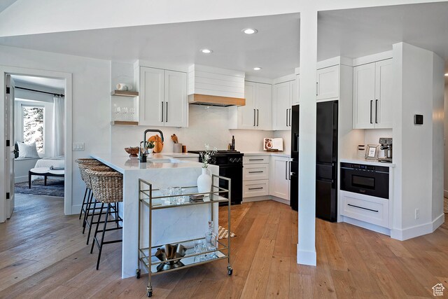 1504 Lake Front Ct, Park City, UT 84098 - kitchen with black appliances, custom range hood, light wood-style floors, a sink, and a kitchen bar