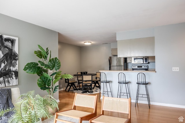 2660 E 3300 S Unit A-21, Salt Lake City, UT 84109 - kitchen featuring stainless steel appliances, light wood-style flooring, a peninsula, a kitchen bar, and baseboards