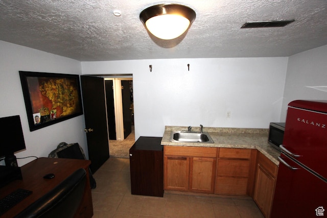 324 W 600 N, Logan, UT 84321 - kitchen with freestanding refrigerator, a sink, stainless steel microwave, brown cabinetry, and a textured ceiling