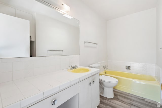 3616 S 860 E Unit 72, Salt Lake City, UT 84106 - bathroom with a bath, wood finished floors, vanity, toilet, and backsplash