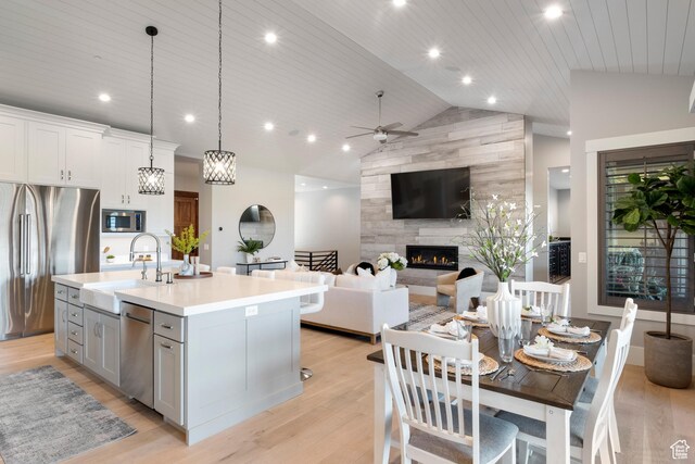 523 N Red Ct, Heber City, UT 84032 - kitchen featuring appliances with stainless steel finishes, a sink, lofted ceiling, a tiled fireplace, and light countertops