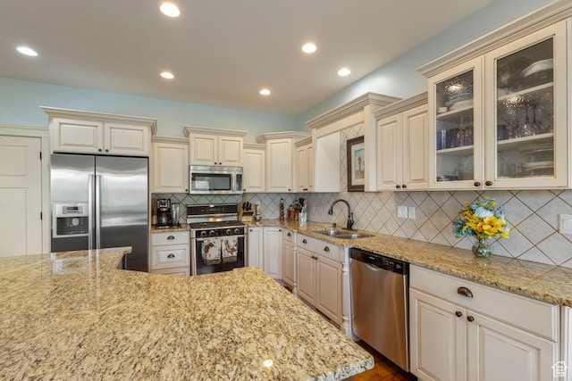 2078 E 3025 N, North Logan, UT 84341 - kitchen with appliances with stainless steel finishes, a sink, cream cabinetry, light stone counters, and tasteful backsplash