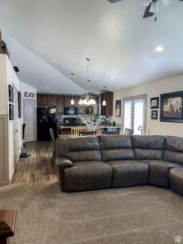 1303 N 150 E, Nephi, UT 84648 - living room featuring a chandelier, lofted ceiling, ceiling fan, dark colored carpet, and dark wood-type flooring