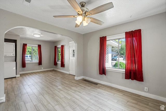 254 Franklin St, Ogden, UT 84401 - empty room featuring stacked washer and clothes dryer, arched walkways, a textured ceiling, baseboards, and a ceiling fan
