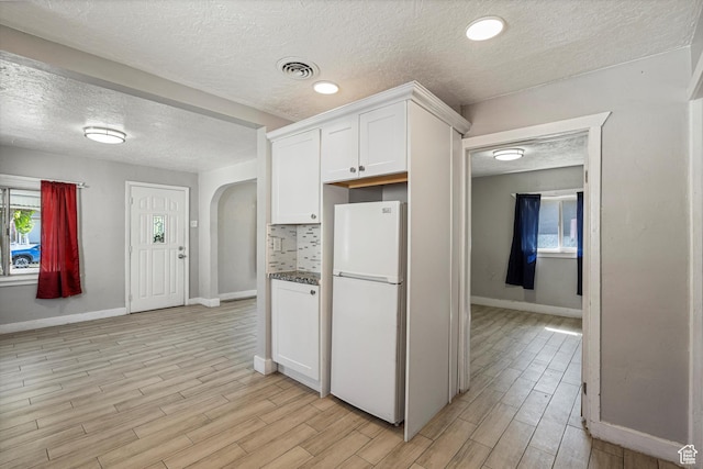 254 Franklin St, Ogden, UT 84401 - kitchen featuring freestanding refrigerator, a textured ceiling, arched walkways, light wood finished floors, and white cabinets