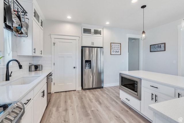 6228 W Copperhawk Dr S, South Jordan, UT 84009 - kitchen featuring appliances with stainless steel finishes, a sink, light wood-style floors, decorative backsplash, and white cabinetry