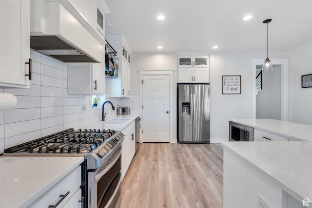 6228 W Copperhawk Dr S, South Jordan, UT 84009 - kitchen with appliances with stainless steel finishes, custom range hood, a sink, tasteful backsplash, and light wood-style floors