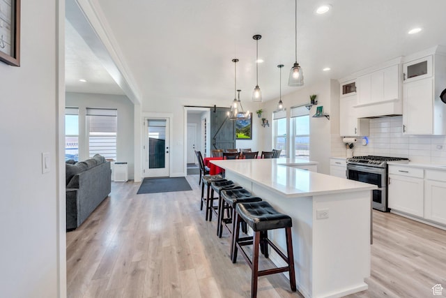 6228 W Copperhawk Dr S, South Jordan, UT 84009 - kitchen with range with two ovens, a barn door, light wood-style flooring, a kitchen island, and tasteful backsplash