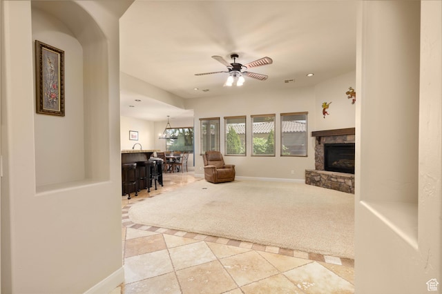 822 E Birken St, Washington, UT 84780 - tiled living area featuring a bar, a stone fireplace, ceiling fan, carpet flooring, and baseboards