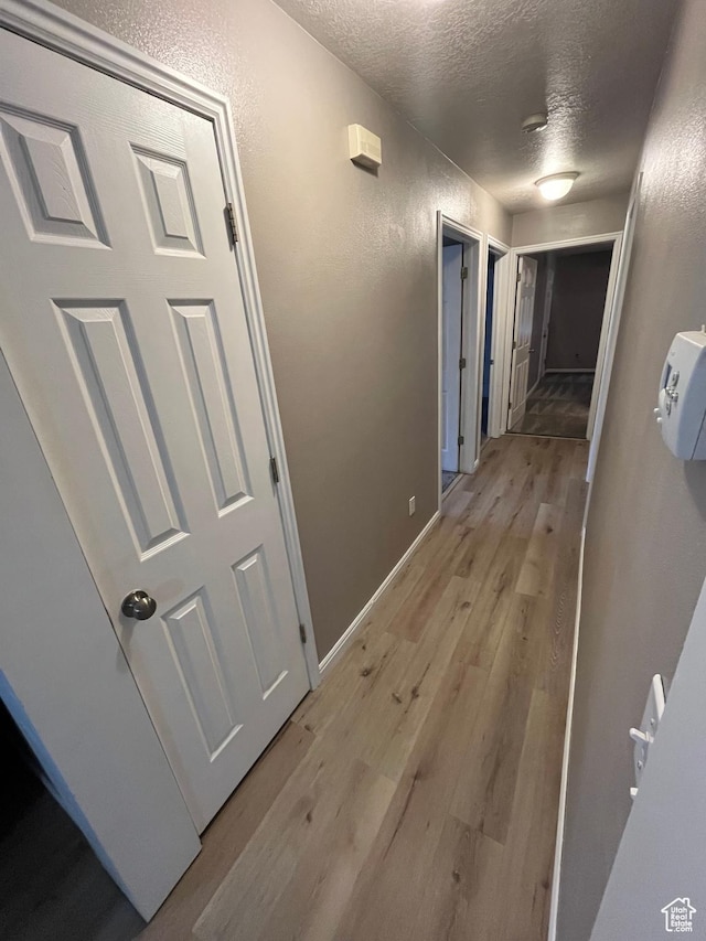 3478 E Rdg Route Rd Unit C1, Eagle Mountain, UT 84005 - corridor with a textured ceiling, a textured wall, light wood finished floors, and baseboards
