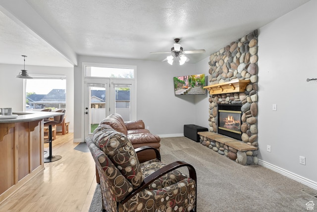 2047 E 1850 S, Spanish Fork, UT 84660 - living room with ceiling fan, a textured ceiling, a stone fireplace, baseboards, and light wood-style flooring