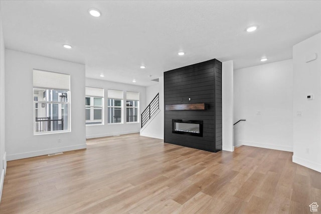 3466 S Peebles Ct E, South Salt Lake, UT 84115 - unfurnished living room featuring light wood finished floors, baseboards, recessed lighting, a large fireplace, and stairway