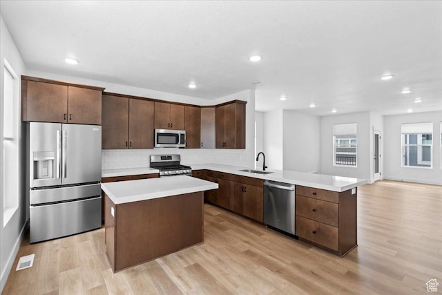 3466 S Peebles Ct E, South Salt Lake, UT 84115 - kitchen featuring stainless steel appliances, backsplash, a peninsula, light countertops, and light wood-style floors