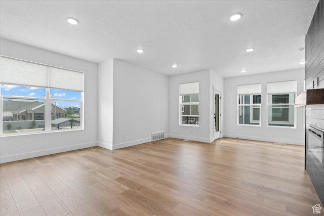 3466 S Peebles Ct E, South Salt Lake, UT 84115 - unfurnished living room featuring light wood-style floors, baseboards, recessed lighting, and a textured ceiling
