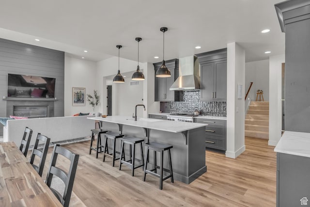 336 Big Meadow Dr, Kamas, UT 84036 - kitchen featuring wall chimney range hood, gray cabinets, a sink, stove, and light wood-style flooring