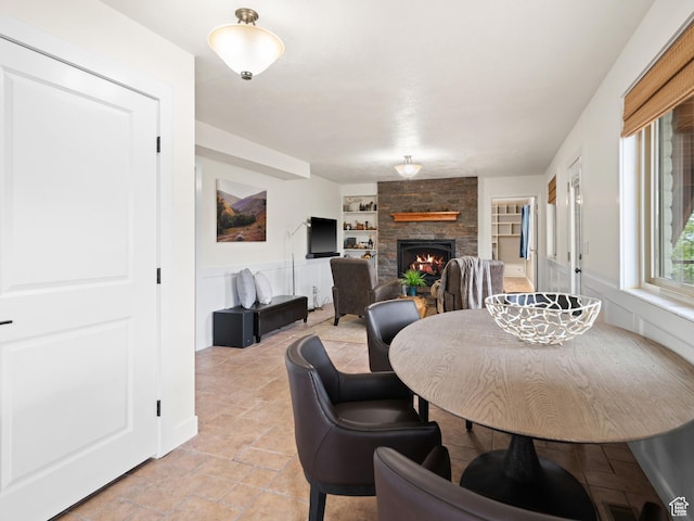 4253 S Spring Rd E, Ogden, UT 84403 - dining space featuring built in shelves, a stone fireplace, and light stone finish floors