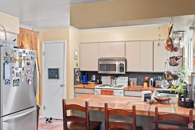 3275 N 250 E, North Ogden, UT 84414 - kitchen with appliances with stainless steel finishes, a sink, white cabinets, tile countertops, and a peninsula
