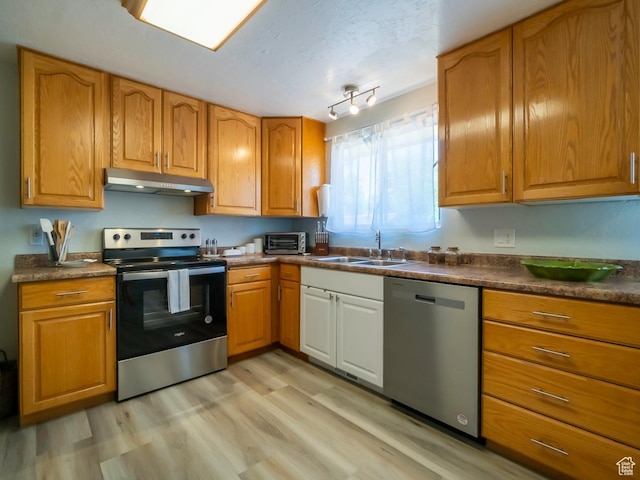 2567 W 2975 S, West Valley City, UT 84119 - kitchen featuring stainless steel appliances, under cabinet range hood, a sink, light wood finished floors, and dark countertops