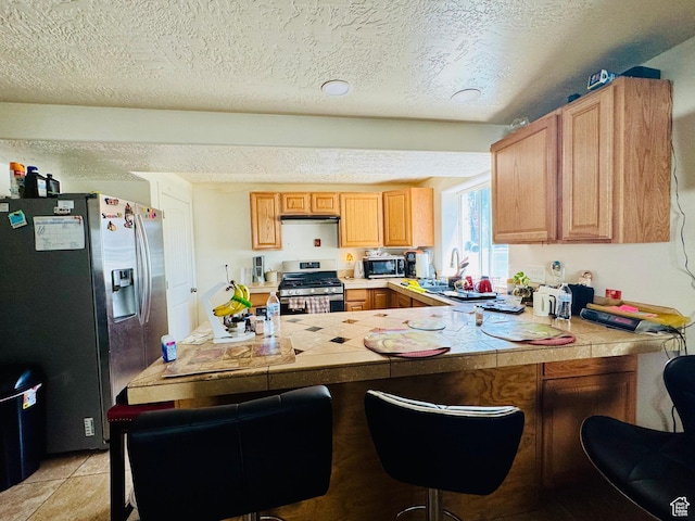 2552 W 2025 N, Clinton, UT 84015 - kitchen featuring stainless steel appliances, a sink, a peninsula, a breakfast bar area, and a textured ceiling