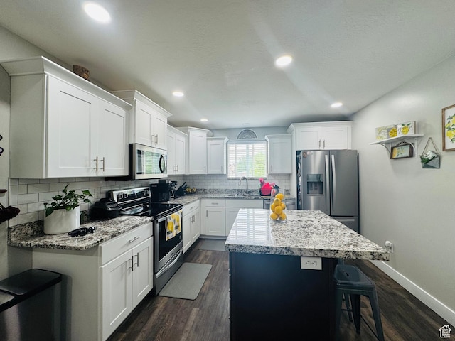 2552 W 2025 N, Clinton, UT 84015 - kitchen featuring appliances with stainless steel finishes, a sink, a center island, a kitchen bar, and tasteful backsplash