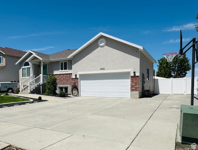 2552 W 2025 N, Clinton, UT 84015 - view of front of home with brick siding, a garage, concrete driveway, and stucco siding