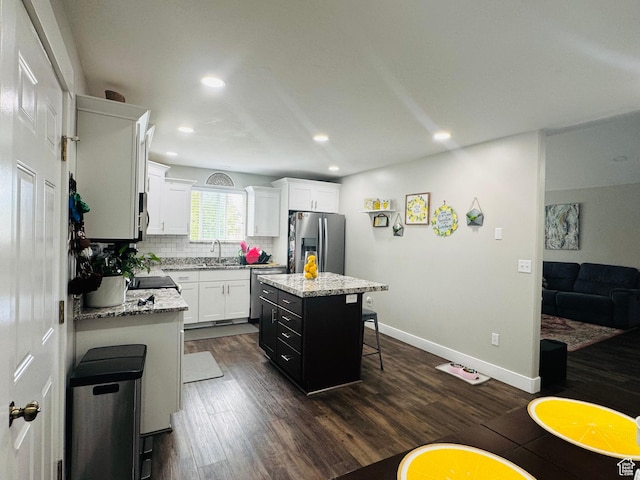 2552 W 2025 N, Clinton, UT 84015 - kitchen with appliances with stainless steel finishes, dark wood-style floors, a breakfast bar, a kitchen island, and white cabinetry