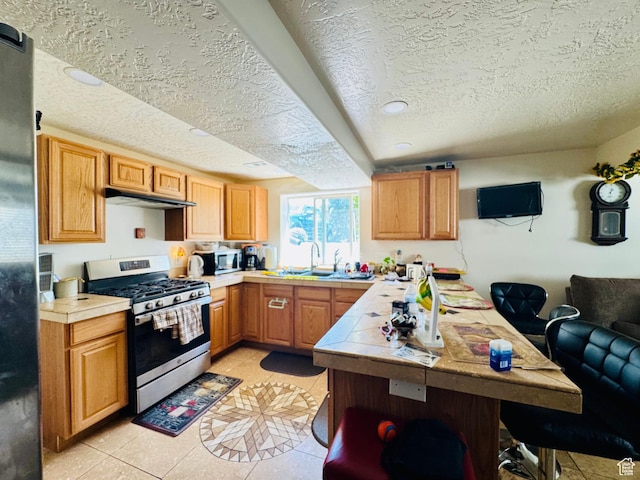 2552 W 2025 N, Clinton, UT 84015 - kitchen featuring appliances with stainless steel finishes, tile counters, a textured ceiling, under cabinet range hood, and a sink