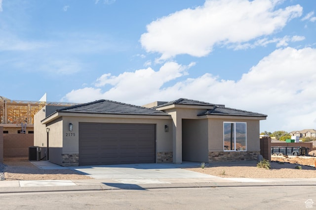 2175 W 320 S, Hurricane, UT 84737 - view of front of home with stone siding, an attached garage, central AC unit, driveway, and stucco siding