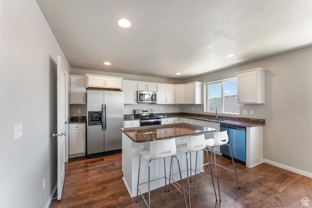 2956 S Willow Creek Dr, Saratoga Springs, UT 84045 - kitchen featuring stainless steel appliances, a sink, white cabinetry, a breakfast bar, and dark wood-style floors