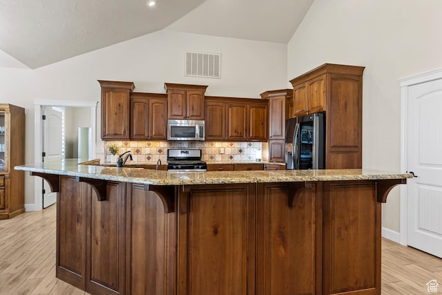 880 N 370 W, La Verkin, UT 84745 - kitchen featuring stainless steel appliances, a kitchen bar, decorative backsplash, high vaulted ceiling, and light stone countertops
