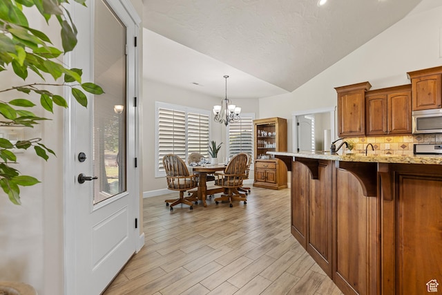880 N 370 W, La Verkin, UT 84745 - kitchen with stainless steel microwave, a kitchen breakfast bar, tasteful backsplash, vaulted ceiling, and light stone counters