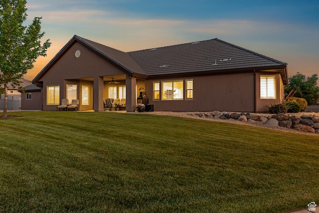 880 N 370 W, La Verkin, UT 84745 - back of house at dusk featuring a ceiling fan, a lawn, a patio, and stucco siding