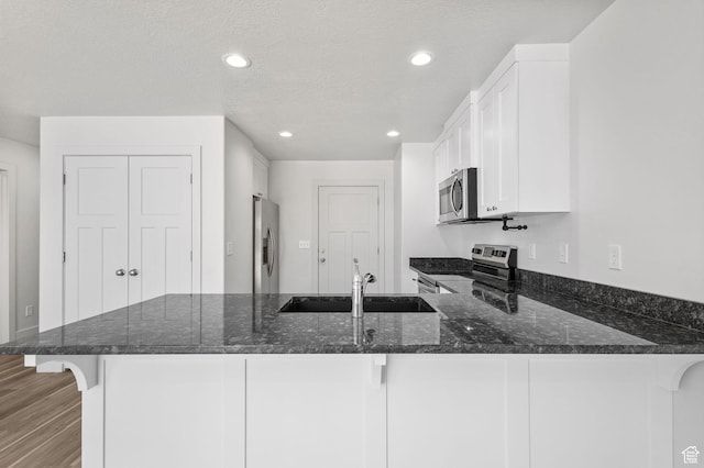 917 N 100 W, Nephi, UT 84648 - kitchen featuring appliances with stainless steel finishes, a sink, a peninsula, dark stone counters, and white cabinetry