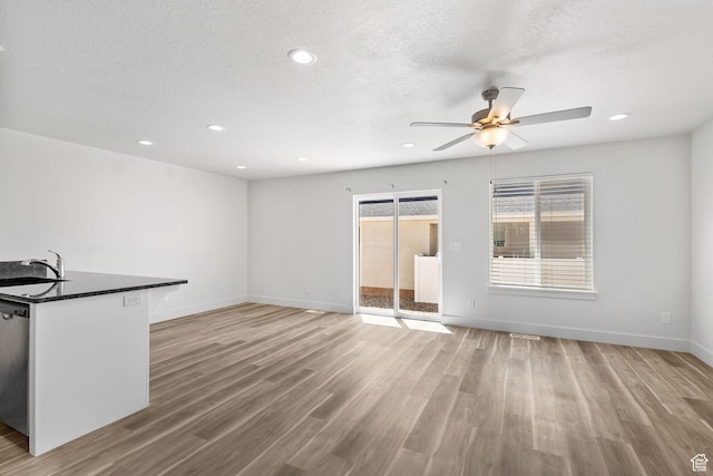 917 N 100 W, Nephi, UT 84648 - unfurnished living room with a ceiling fan, light wood-style floors, a sink, baseboards, and a textured ceiling