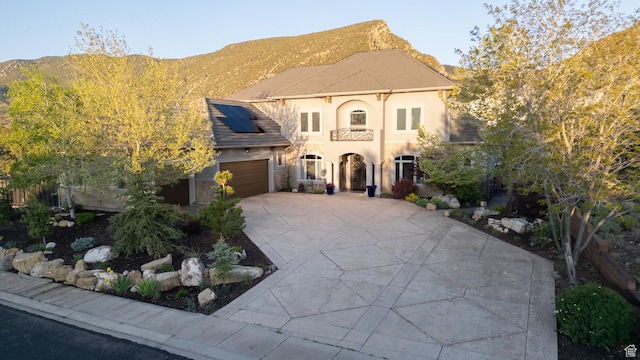2204 N Bridge Water Rd, Cedar City, UT 84721 - view of front of home featuring stucco siding, roof mounted solar panels, concrete driveway, an attached garage, and a mountain view