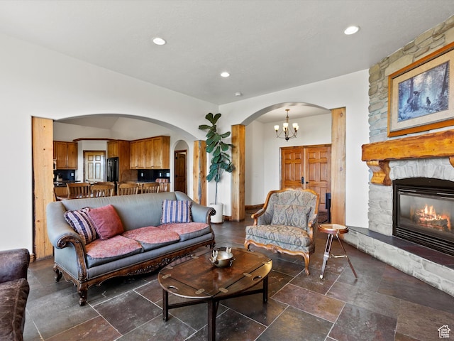 5577 E Elkhorn Dr, Eden, UT 84310 - living area featuring arched walkways, stone tile flooring, a stone fireplace, recessed lighting, and a chandelier