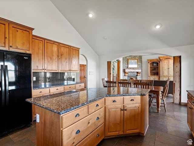 5577 E Elkhorn Dr, Eden, UT 84310 - kitchen featuring freestanding refrigerator, arched walkways, decorative backsplash, a kitchen island, and high vaulted ceiling