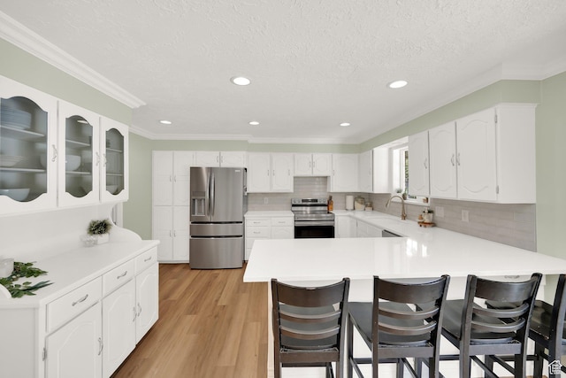 1607 Mountain Cir, Fruit Heights, UT 84037 - kitchen with appliances with stainless steel finishes, a peninsula, a breakfast bar area, tasteful backsplash, and light wood finished floors